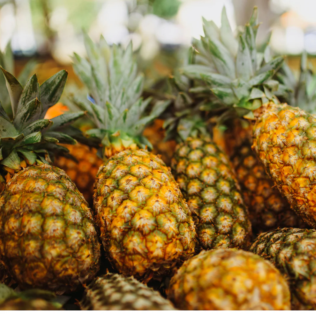 Fresh pineapples clustered together at market.