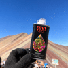 Gloved hand holds buriti oil bottle before colorful mountain