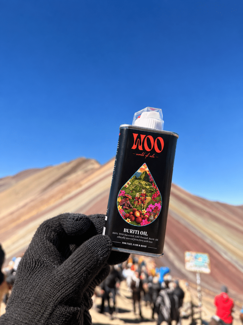 Gloved hand holds buriti oil bottle before colorful mountain