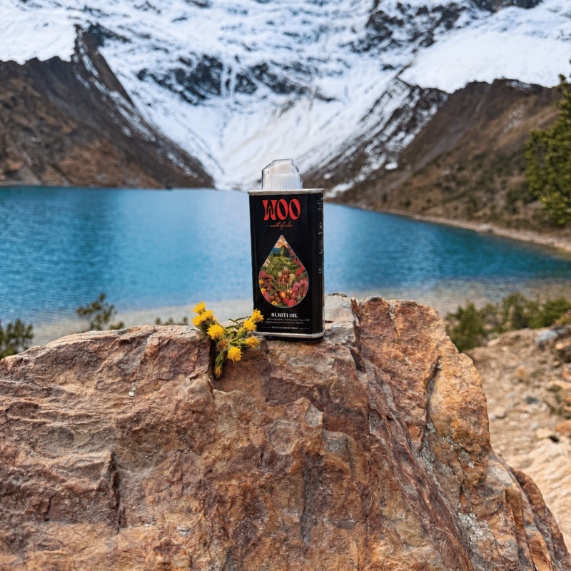 Buriti Oil Beneath Alpine Peaks Buriti oil bottle on rock above turquoise glacial lake