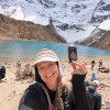 Hiker holds tea can beside turquoise alpine lake