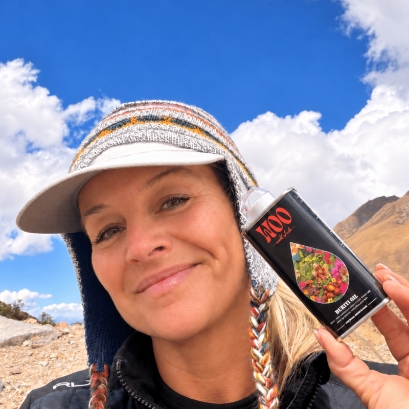 Mountain Selfie with Buriti Oil Tin Hiker holding Buriti oil bottle beneath blue mountain sky